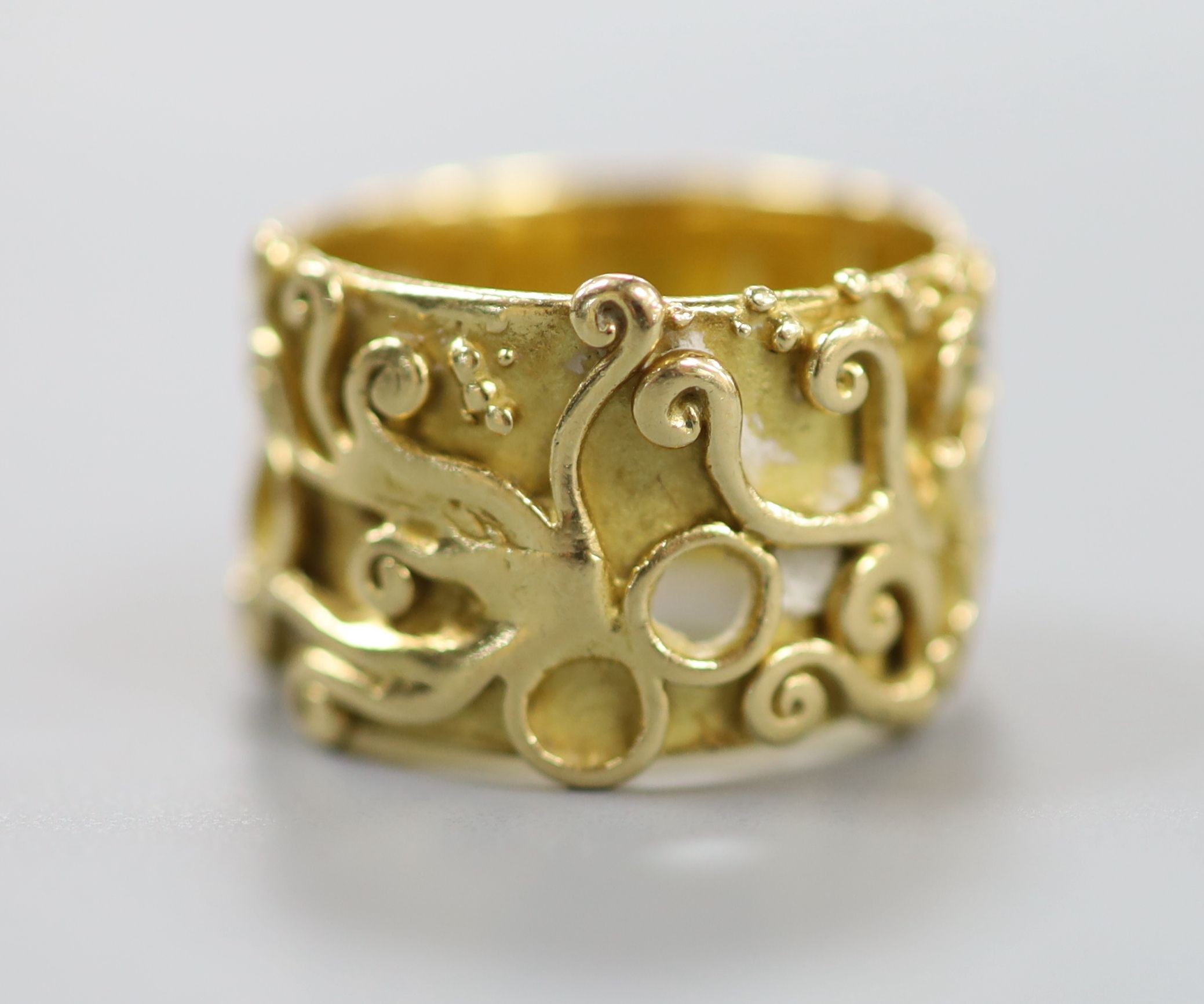 An 18ct Welsh gold band, with pierced and scroll decoration, size O, 11.8 grams.